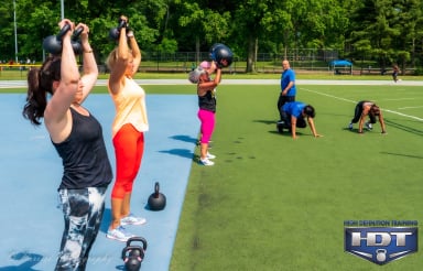 Group workout session in a park with kettlebells and fitness exercises.