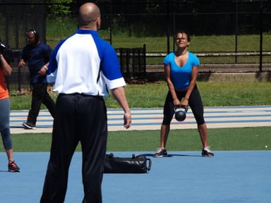 A woman exercises with a kettlebell during outdoor training.