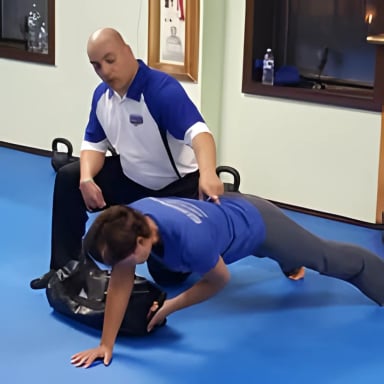 Personal trainer assisting client with exercise on mat