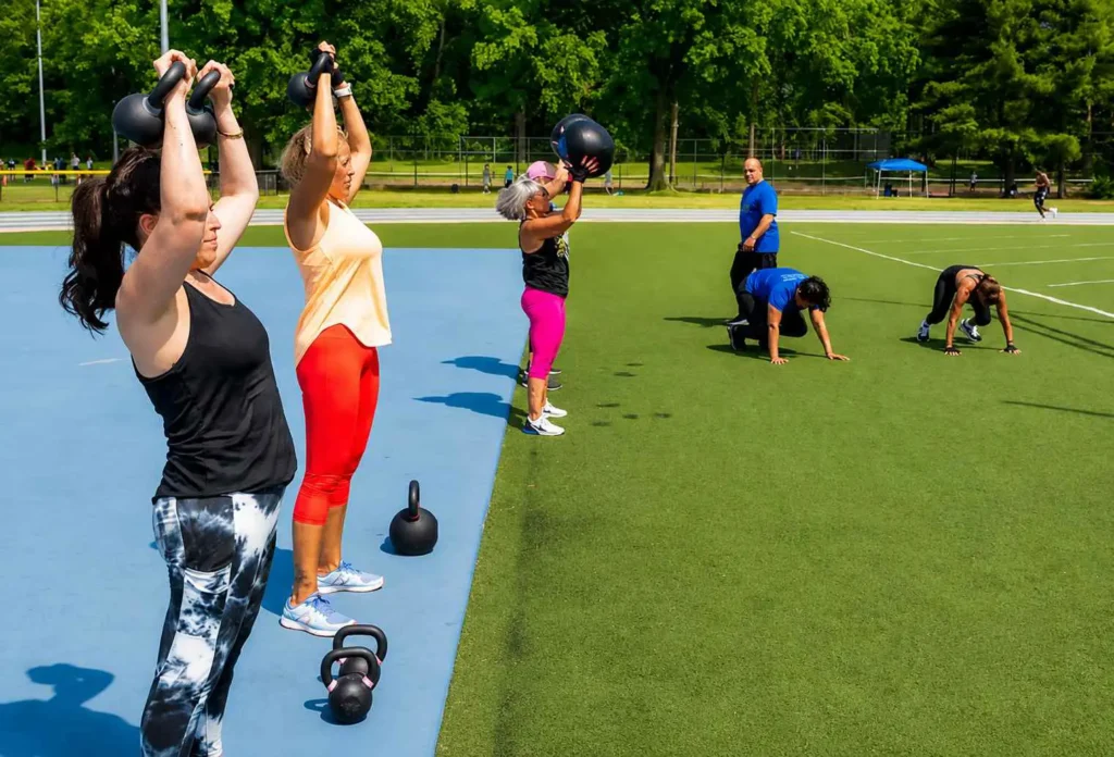 Women performing kettlebell exercises during an outdoor group fitness session