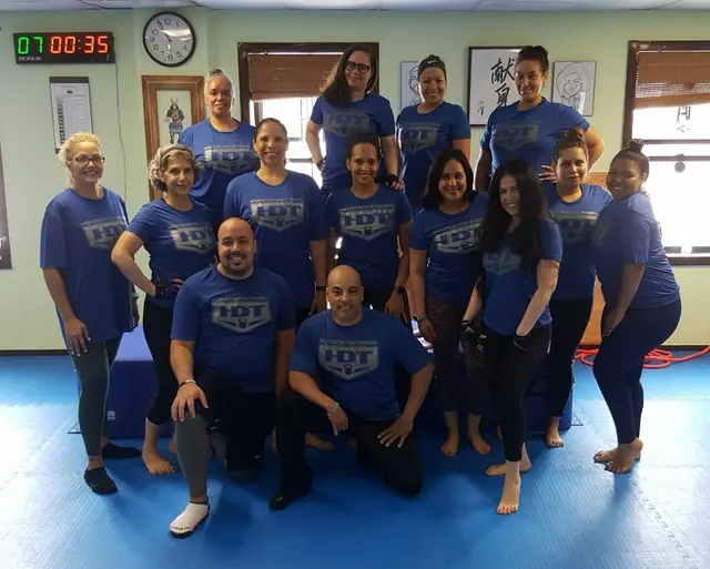 Fitness training group posing together in matching shirts after indoor workout