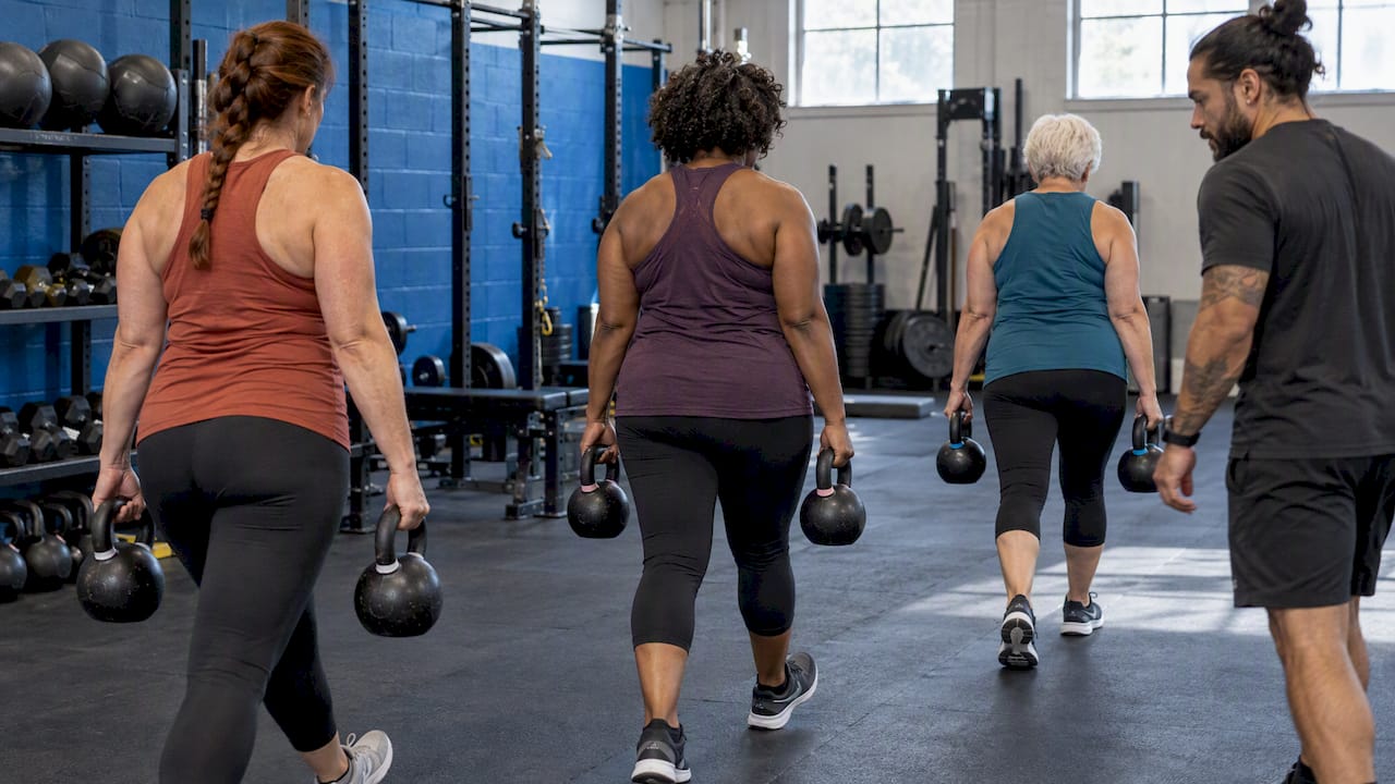 Women carrying kettlebells together in a gym